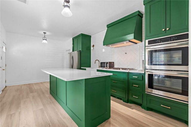 kitchen with a center island, stainless steel appliances, green cabinets, custom range hood, and light wood-type flooring