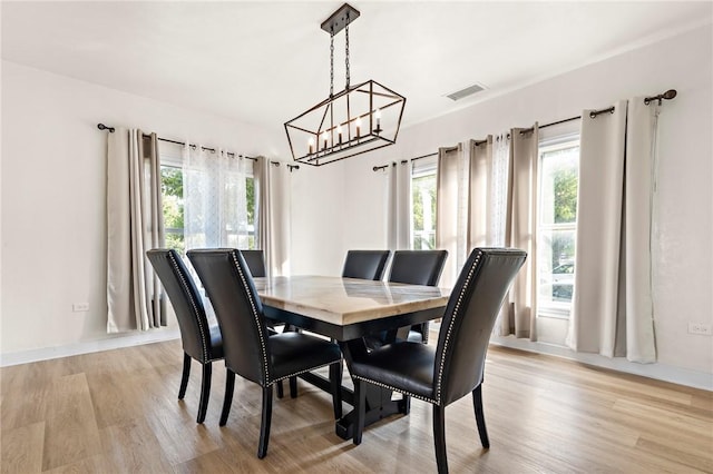 dining space with light hardwood / wood-style flooring and a notable chandelier