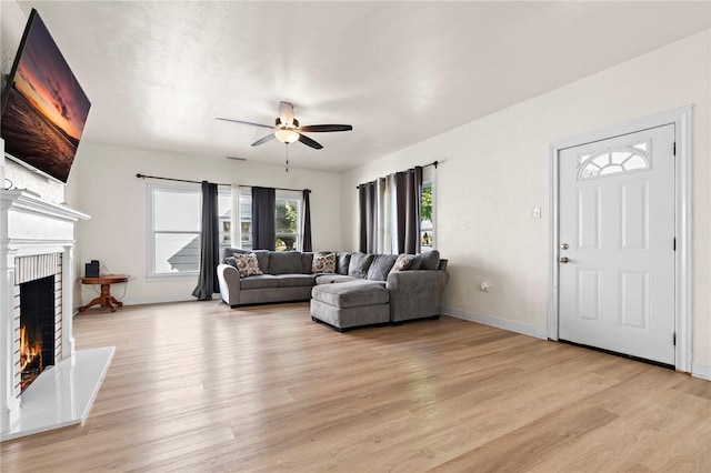 living room featuring a fireplace, light hardwood / wood-style floors, and ceiling fan