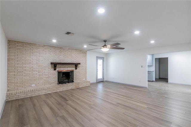 unfurnished living room with a fireplace, light wood-type flooring, and ceiling fan