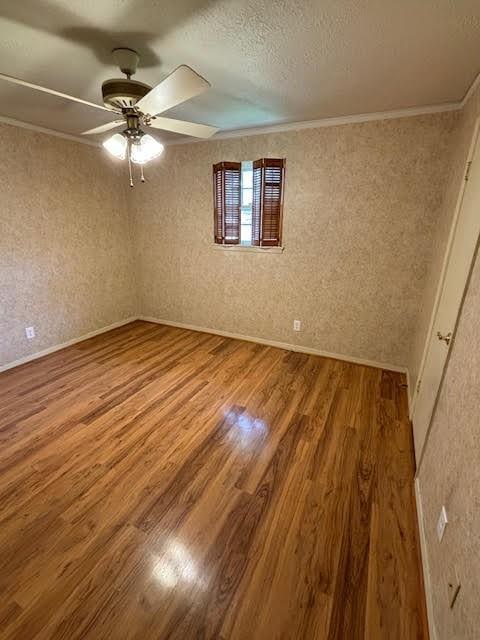 spare room with hardwood / wood-style flooring, ceiling fan, ornamental molding, and a textured ceiling