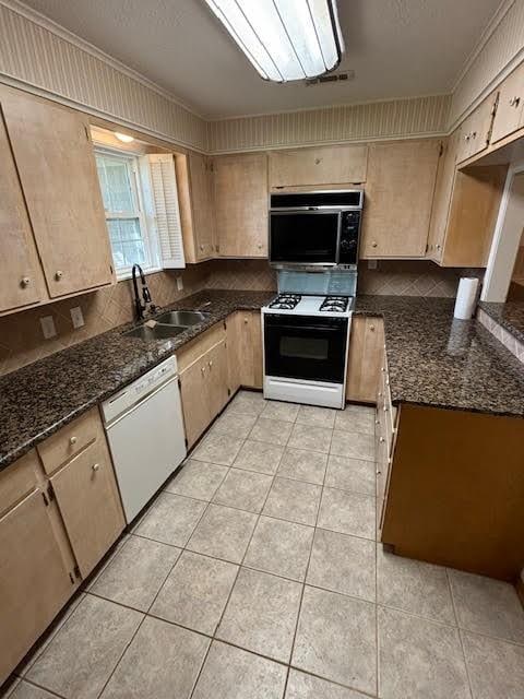 kitchen with dark stone countertops, sink, white appliances, and ornamental molding