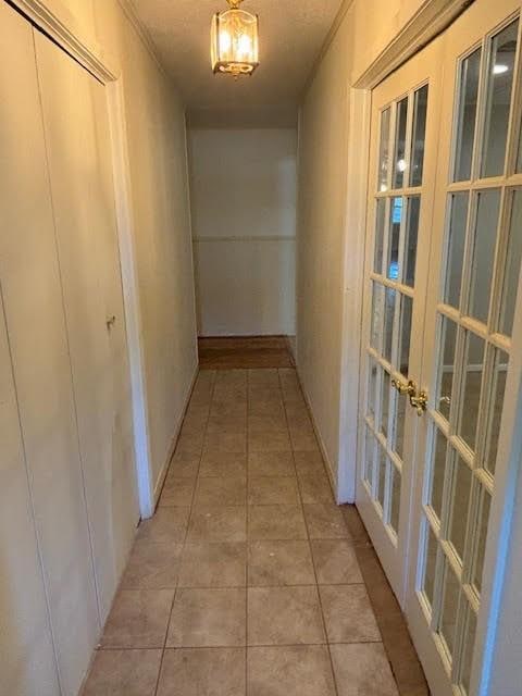 hallway with french doors and light tile patterned floors