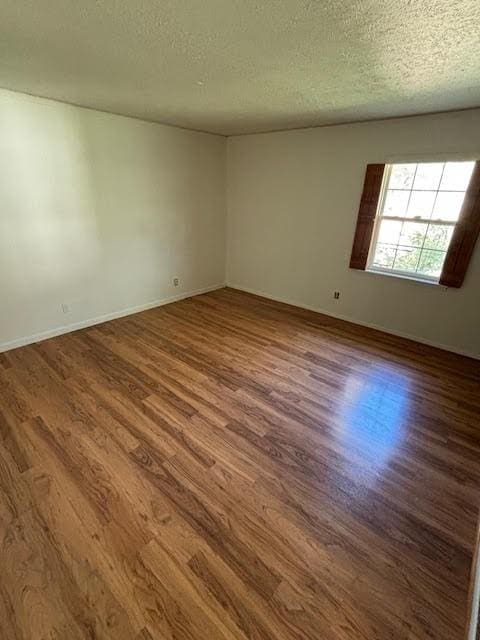 unfurnished room with hardwood / wood-style floors and a textured ceiling