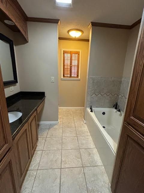 bathroom with tile patterned floors, tiled bath, vanity, and ornamental molding