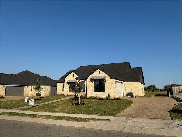 view of front of home featuring a garage, a front lawn, and central air condition unit