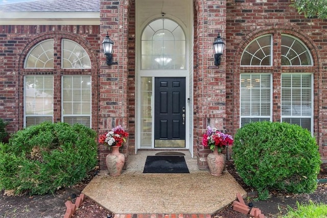 entrance to property featuring brick siding and roof with shingles