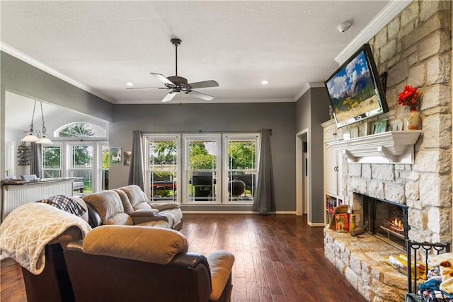 living room with dark wood-type flooring, ceiling fan, ornamental molding, a textured ceiling, and a fireplace