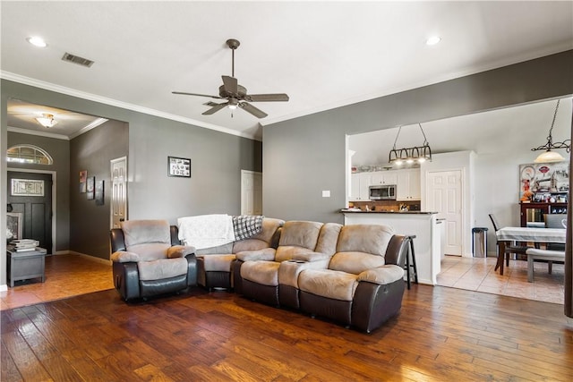 living room with hardwood / wood-style flooring, ceiling fan, and crown molding