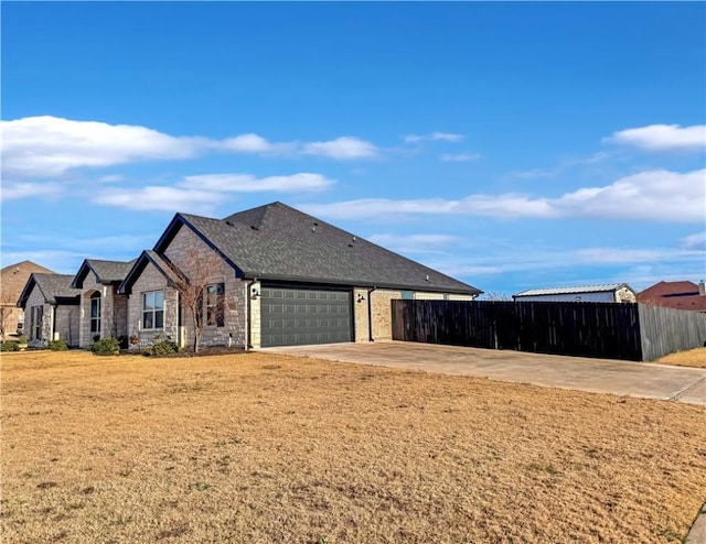 view of side of property with roof with shingles, a yard, fence, a garage, and stone siding