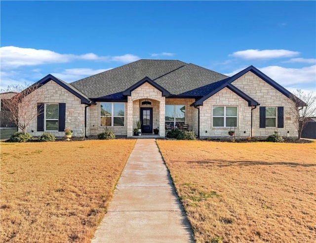 french country inspired facade with a front yard and roof with shingles