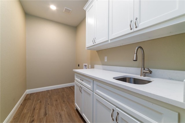 laundry area with electric dryer hookup, cabinets, sink, hardwood / wood-style flooring, and washer hookup