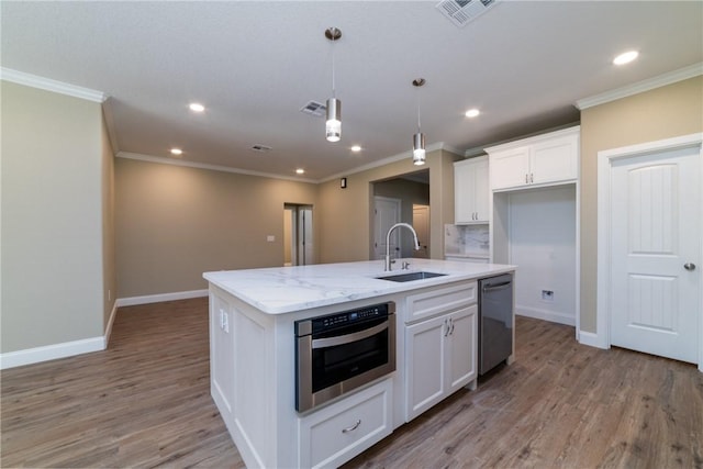 kitchen featuring white cabinets, sink, an island with sink, and decorative light fixtures