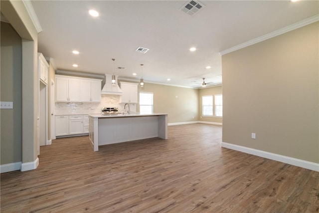 kitchen featuring white cabinets, hardwood / wood-style floors, a center island with sink, and custom exhaust hood