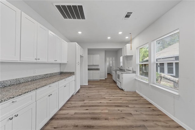 kitchen featuring white cabinetry, white range with electric cooktop, light stone countertops, and light wood-type flooring