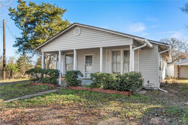 bungalow-style home featuring covered porch and a front lawn