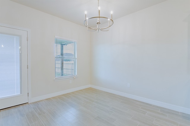 spare room with a chandelier and light wood-type flooring