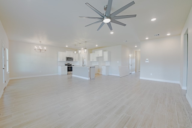 unfurnished living room with ceiling fan with notable chandelier and light wood-type flooring