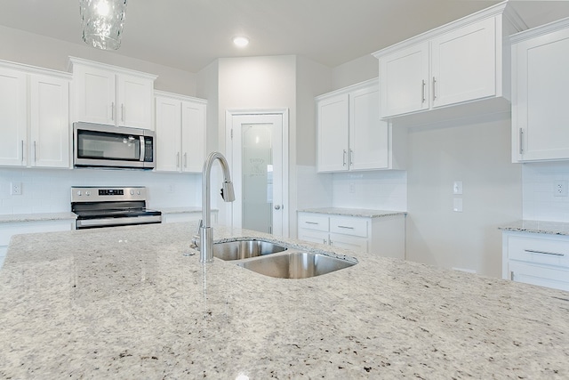 kitchen with light stone countertops, white cabinetry, sink, and appliances with stainless steel finishes