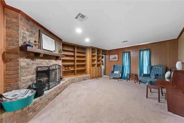 living area featuring built in features, wooden walls, a fireplace, carpet flooring, and crown molding