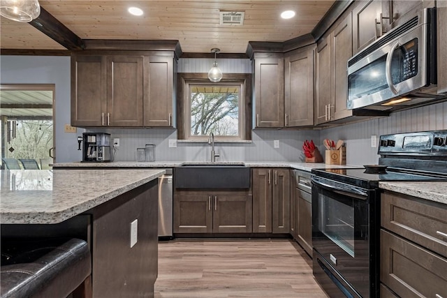 kitchen with pendant lighting, black / electric stove, dark brown cabinets, and light hardwood / wood-style floors