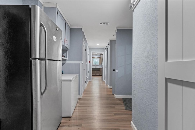 kitchen featuring white cabinetry, washer / dryer, wood-type flooring, and stainless steel refrigerator