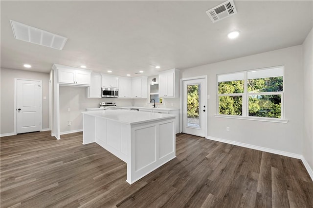 kitchen with a center island, dark wood-type flooring, white cabinets, sink, and appliances with stainless steel finishes