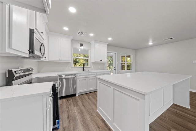 kitchen with a center island, sink, stainless steel appliances, wood-type flooring, and white cabinets