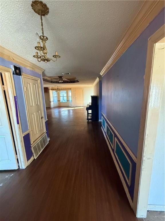 corridor featuring dark hardwood / wood-style flooring, a textured ceiling, an inviting chandelier, and crown molding