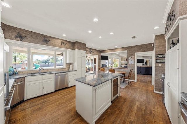 kitchen with stainless steel dishwasher, beverage cooler, white cabinetry, and hardwood / wood-style flooring