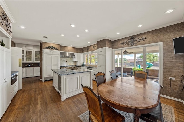 kitchen with dark wood-type flooring, dark stone counters, ornamental molding, tasteful backsplash, and white cabinetry