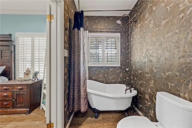 bathroom with a bathing tub, hardwood / wood-style floors, ornamental molding, and toilet