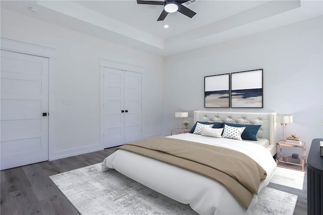 bedroom featuring ceiling fan, dark hardwood / wood-style floors, a closet, and a tray ceiling