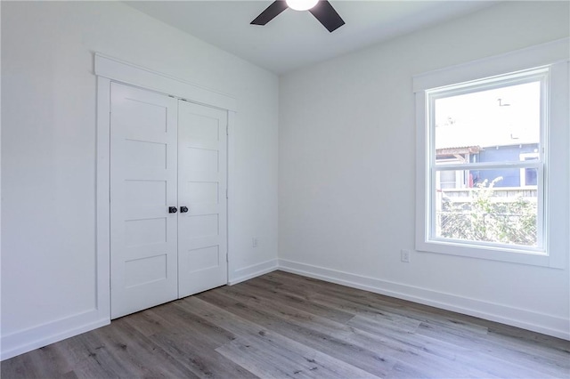 unfurnished bedroom with ceiling fan, a closet, and wood-type flooring