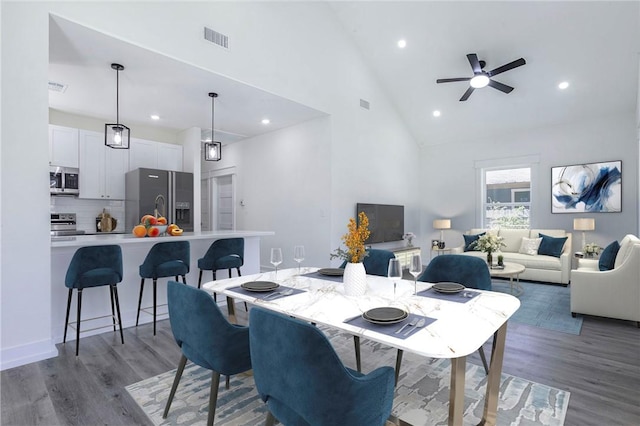 dining area with ceiling fan, hardwood / wood-style floors, and high vaulted ceiling