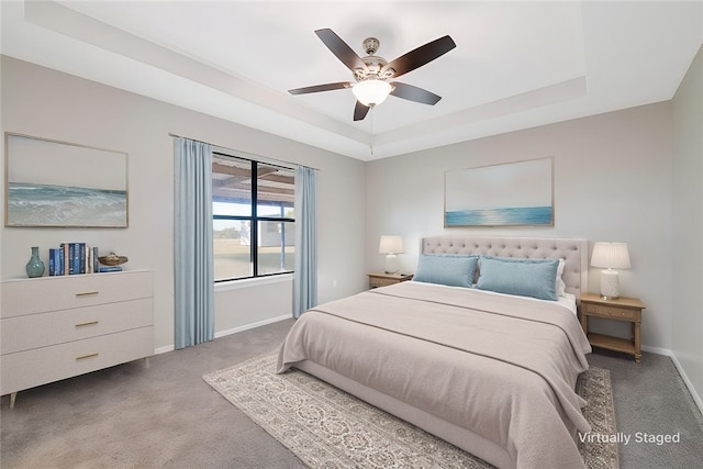 carpeted bedroom featuring a tray ceiling and ceiling fan