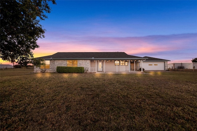 ranch-style home with a porch, a garage, and a yard