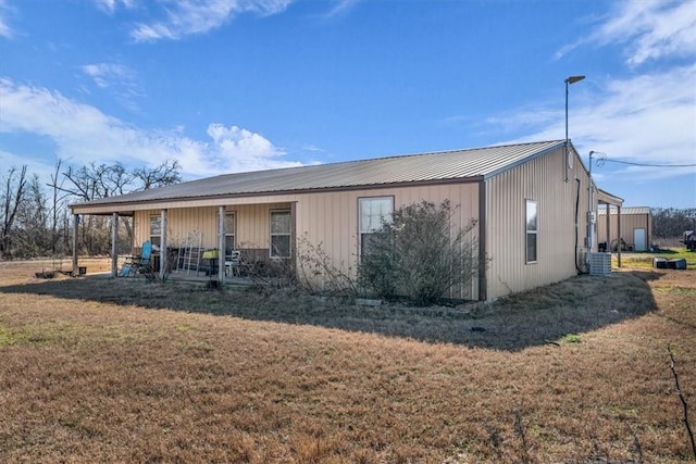 back of property featuring covered porch, metal roof, cooling unit, and a yard