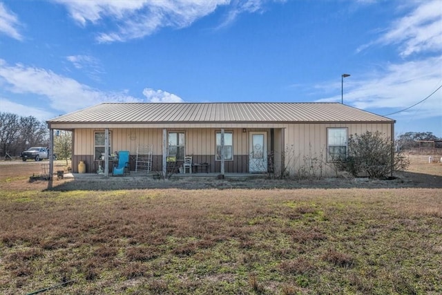 view of front of house with covered porch, metal roof, and a front lawn