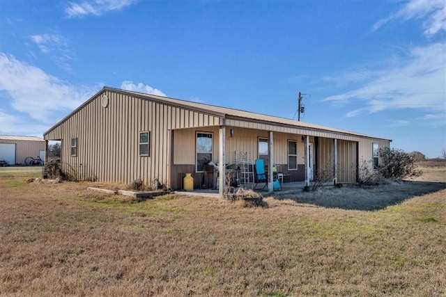 back of property featuring a porch, board and batten siding, and a yard