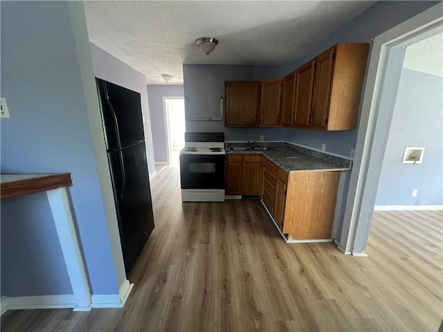 kitchen with black fridge, sink, white electric stove, hardwood / wood-style flooring, and a textured ceiling