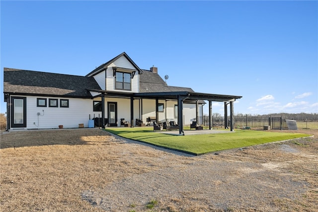 rear view of house with a patio, a yard, a chimney, and fence