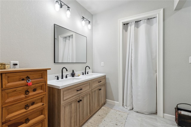 bathroom with double vanity, baseboards, and a sink