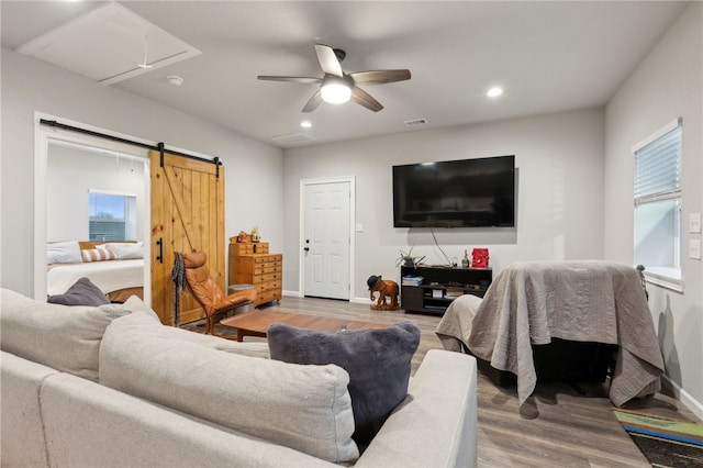 living room with attic access, a barn door, baseboards, visible vents, and wood finished floors