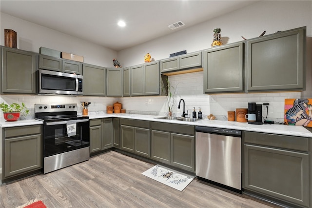 kitchen featuring light wood finished floors, stainless steel appliances, light countertops, visible vents, and a sink