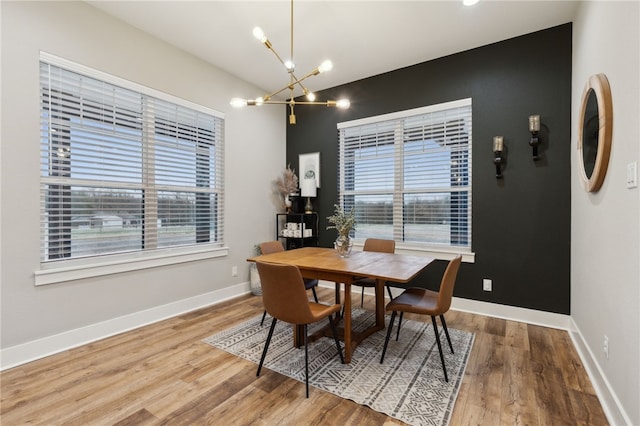 dining area featuring baseboards, a chandelier, and wood finished floors