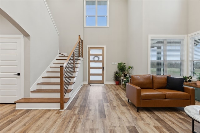 foyer featuring stairs, a towering ceiling, baseboards, and wood finished floors