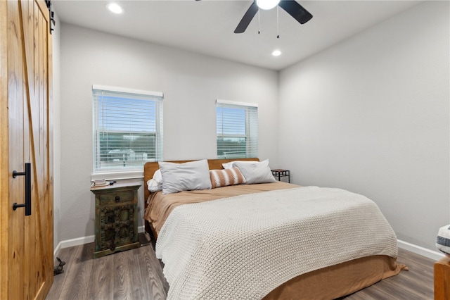 bedroom with a barn door, baseboards, dark wood-type flooring, and recessed lighting