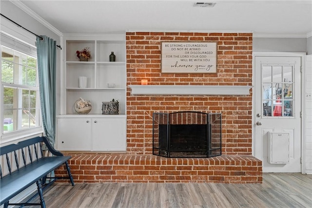 living room featuring crown molding, hardwood / wood-style floors, and a brick fireplace