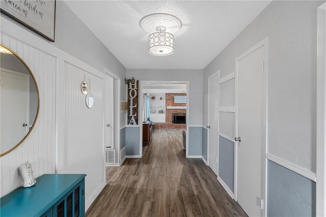 hall with dark wood-type flooring and a textured ceiling